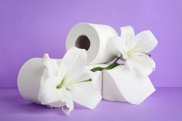 Rolls of toilet paper and flowers on color background