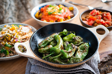 Padron peppers in a pan with other healthy vegetarian food in background
