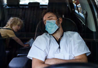 Tired and exhausted doctor sitting in car after long and difficult shift, sleeping.
