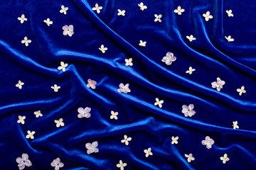 Lilac petals are scattered on blue velvet like stars