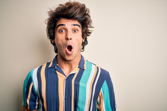 Young man on vacation wearing summer colorful shirt standing over isolated white background afraid and shocked with surprise expression, fear and excited face.