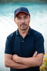 portrait of a man in a baseball cap on a background of blue water