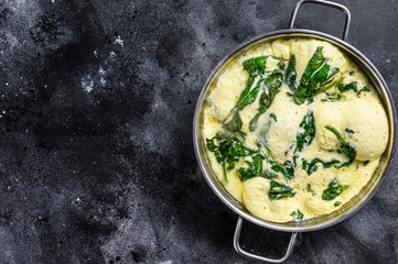 Italian Spinach and Cheese Omelet in a pan.  Black background. Top view. Copy space
