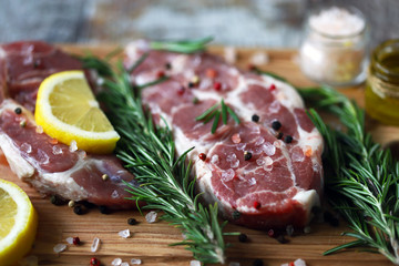 Raw meat steaks on a cutting board. Fresh meat with rosemary and spices. Pork chops. Selective focus. Macro.