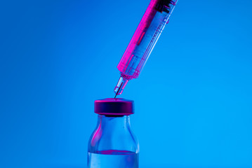 Photo of vaccine vial with syringe isolated over blue background. Medical concept shows a medical...