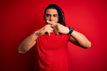 Young handsome african american afro man with dreadlocks wearing red casual t-shirt Rejection expression crossing fingers doing negative sign