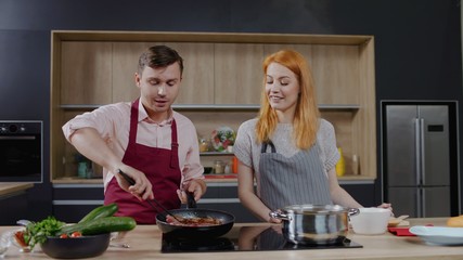 Cooking show hosts chefs, male and female, cooking meat. Morning TV cooking programme