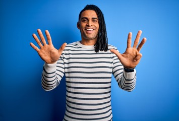 Young handsome african american afro man with dreadlocks wearing casual striped sweater showing and...