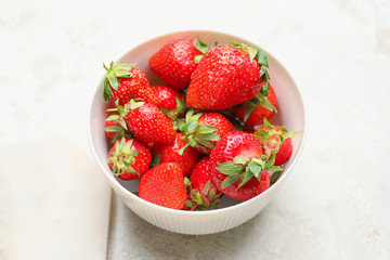 Bowl with ripe strawberry on light background