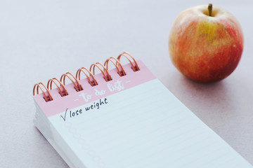notebook with the inscription lose weight, a tick and an apple, diet 