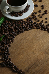 White coffee cup and coffee beans on wooden table with copyspace for text. Selective focus.