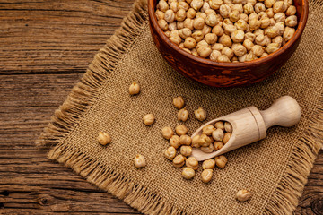 Dry chickpea in ceramic bowl on old wooden boards background. Traditional ingredient for cooking...