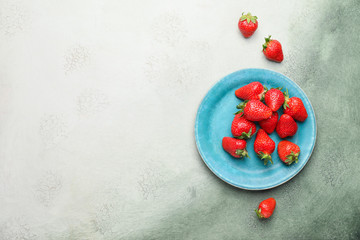 Plate with ripe strawberry on color background