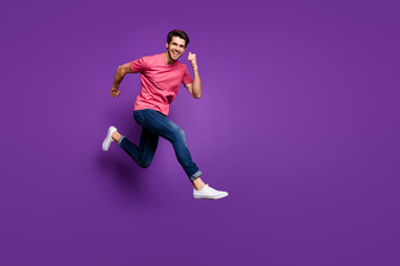Fototapeta na wymiar Full size profile photo of handsome attractive guy jump high up run shopping center sale prices wear casual pink t-shirt jeans footwear isolated purple color background