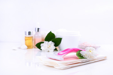 Obraz na płótnie Canvas a set of different means for epilation on a colored background. Removal of unwanted hair. Body care products, creams, emulsion, towel, jasmine flowers, wax strips, razor. Minimalism, top view. flatlay
