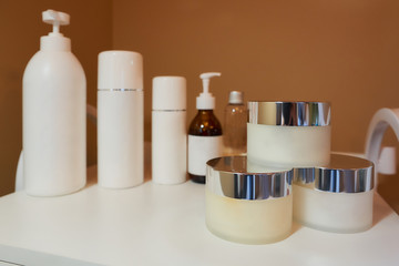 All kinds of skincare products on a white trolley cart in a cosmetology office.