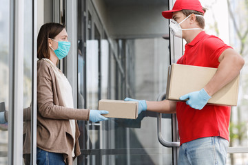 Courier in medical mask and gloves gives box to client, on porch