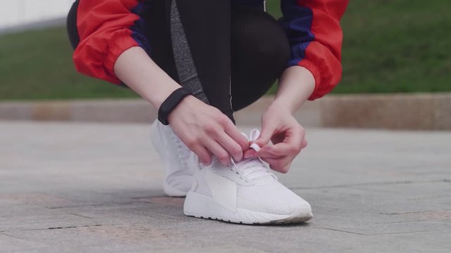 Young sporty female tying shoe lace and strating running