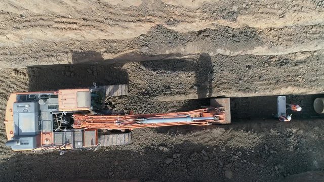 Men at work outdoor outside with heavy machinery loading arm installing water pipeline. Drone above excavating bulldozer or tractor digging and land cleaning soil land. 
