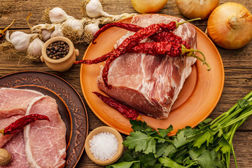 Assorted raw pork meat. Fresh loin, spices, fragrant vegetables and parsley