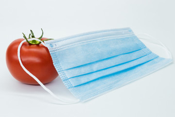 tomato in a medical mask. White background. isolate.  protective mask. vegetables. Coronovaris...