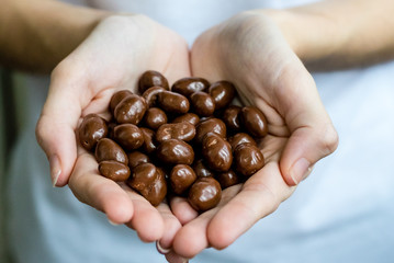 The girl generously treats friends with chocolates. Chocolate in the hand.