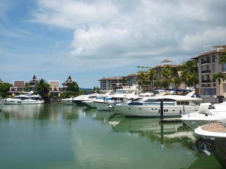 Fototapeta na wymiar Panoramic view of the promenade of a coastal town. City block for rich. Residential homes and moored yachts nearby. Luxury and wealth. Villas and apartments. Yacht club, hotel. Cloudy, calm, nobody