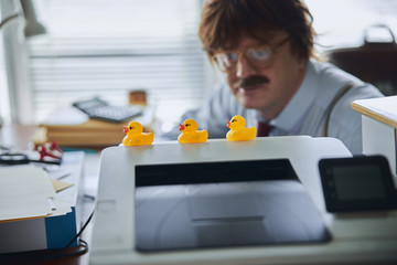Office clerk getting distracted from work by toy rubber ducks