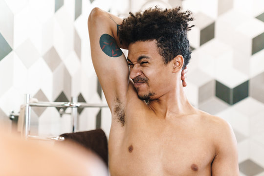 Photo Of African American Man Smelling His Armpits And Looking At Mirror