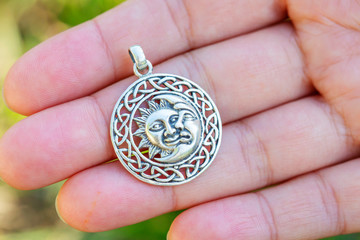Sterling silver pendant in the shape of sun and moon on female hand