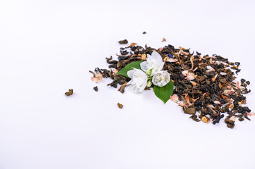 Jasmine tea in a glass on a white background. White flowers with leaves and dried tea for brewing and making a fragrant drink. Aromatherapy and wellness. Free space for text. Copy space
