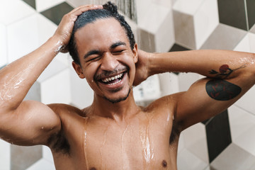 Photo of half-naked african american man smiling while taking shower