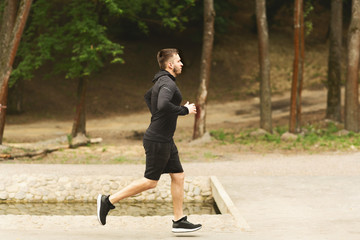 Portrait of focused jogging man running in park