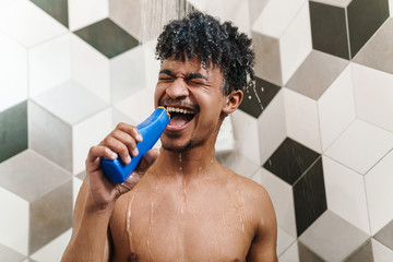 Photo of half-naked african american man making fun while taking shower