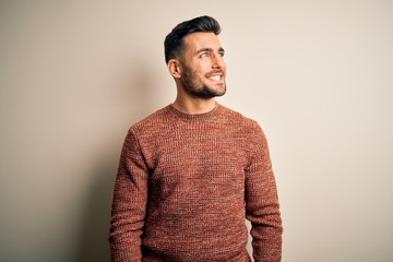 Obraz premium Young handsome man wearing casual sweater standing over isolated white background looking away to side with smile on face, natural expression. Laughing confident.
