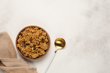 Wooden bowl with Granola,brown kitchen towel and spoon on light background.Top view with copy space.