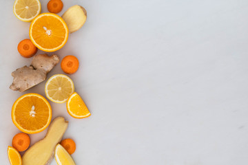 Top down view of citrus fruits ginger root and carrot slices in a flat lay style on left side of...