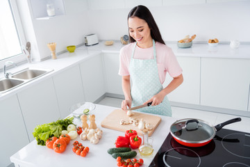 Photo of beautiful asian ethnicity housewife hold knife cut down fresh mushrooms weekend cooking tasty breakfast salad vegan concept stand good mood kitchen indoors