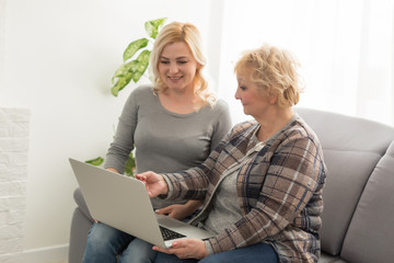 Cheerful elderly woman and smiling girl choosing purchases online. Focus on mature