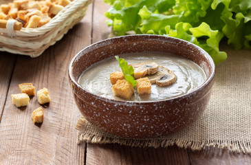 Mushroom cream soup with croutons on a wooden table.
