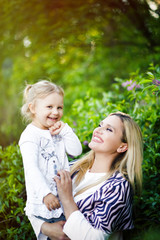 Lifestyle vertical portrait blonde mom and daughter outdoors. Mother and child girl hugging and having fun outdoor in nature. Woman looking on kid. Mother day. Love, trust, togetherness in family.
