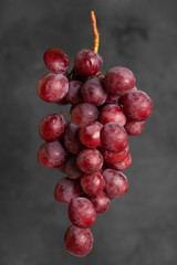 Flying food - Bunch of red grapes besides concrete background.  