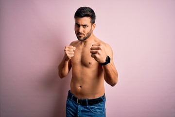 Young handsome strong man with beard shirtless standing over isolated pink background Punching fist to fight, aggressive and angry attack, threat and violence