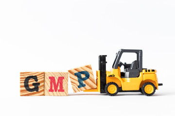 Toy forklift hold wood letter block P to complete word GMP (Abbreviation of Good Manufacturing Practice) on white background
