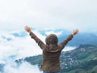 Back view happy woman tourist raise arm on the mountain.