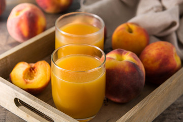 Natural peach juice in glass on wooden table	