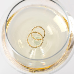 Wedding golden rings in glass of champagne. Symbol of love and marriage.