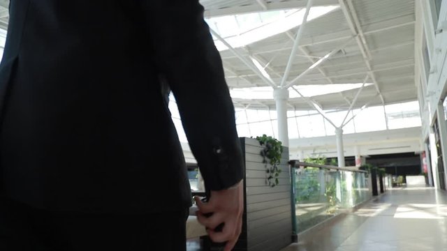 A security guard walks around the supermarket and holds a walkie-talkie in his hand.