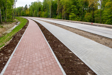 new modern tile sidewalk near a road under construction