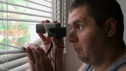 A strange man looks through binoculars